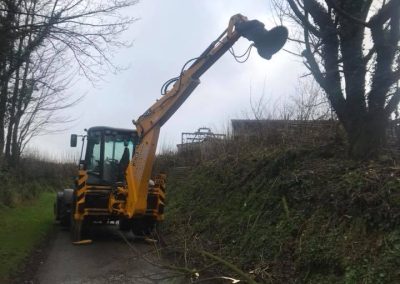 Image of a JCB cutting a hedge with the Image of the Slanetrac HS75 JCB Saw Head attachment